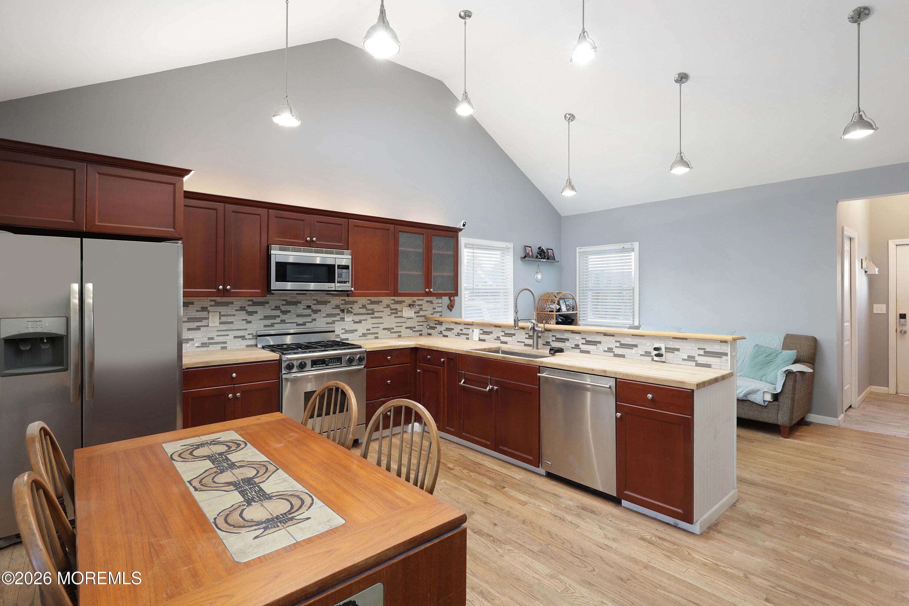 24 West Point Pleasant Avenue Ocean Gate, NJ 08740 - Photo 9 of 23 a kitchen with a stove a sink dishwasher a refrigerator and wooden cabinets with wooden floor
