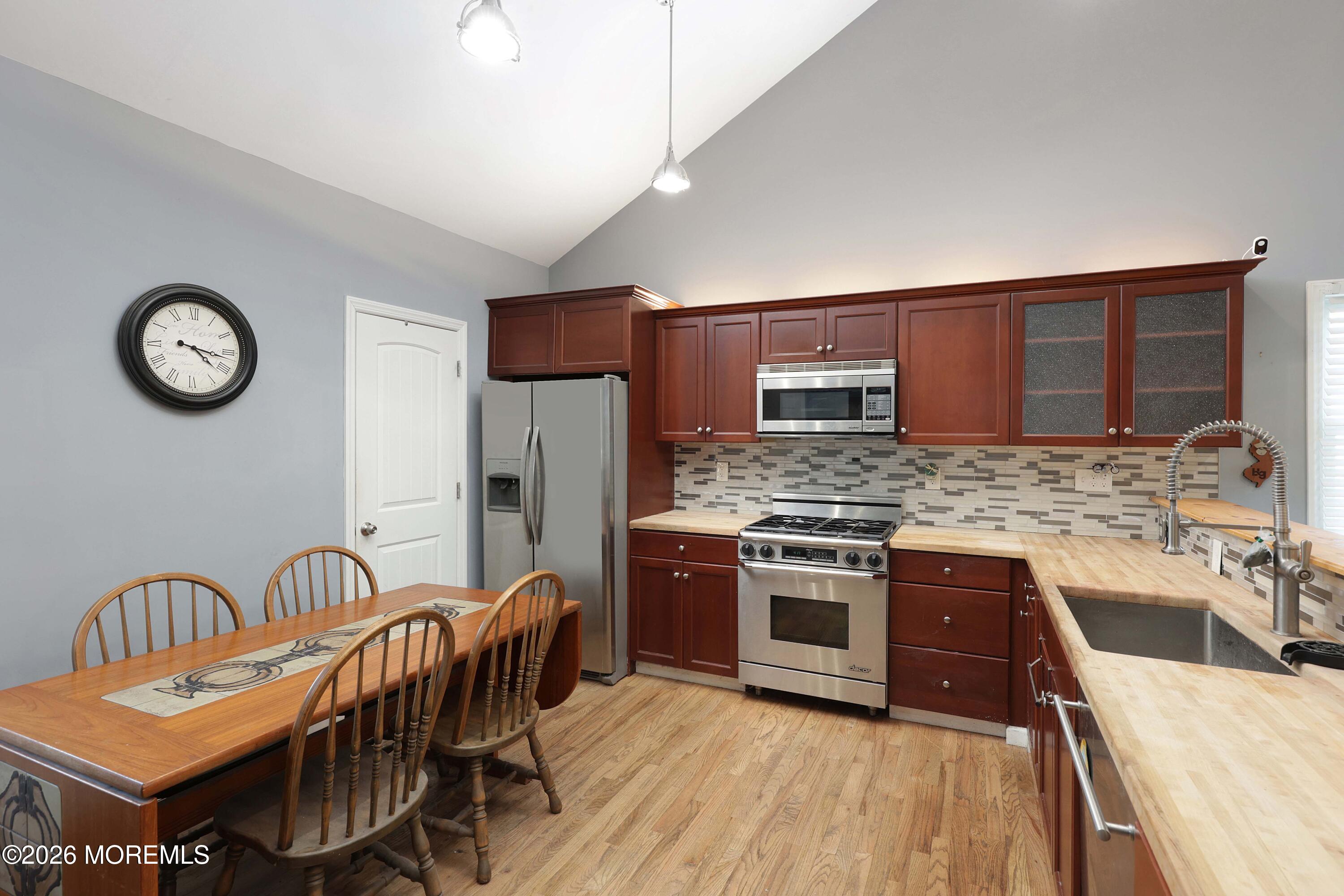 24 West Point Pleasant Avenue Ocean Gate, NJ 08740 - Photo 10 of 23 a kitchen with stainless steel appliances granite countertop a stove top oven a sink dishwasher a dining table and chairs with wooden floor