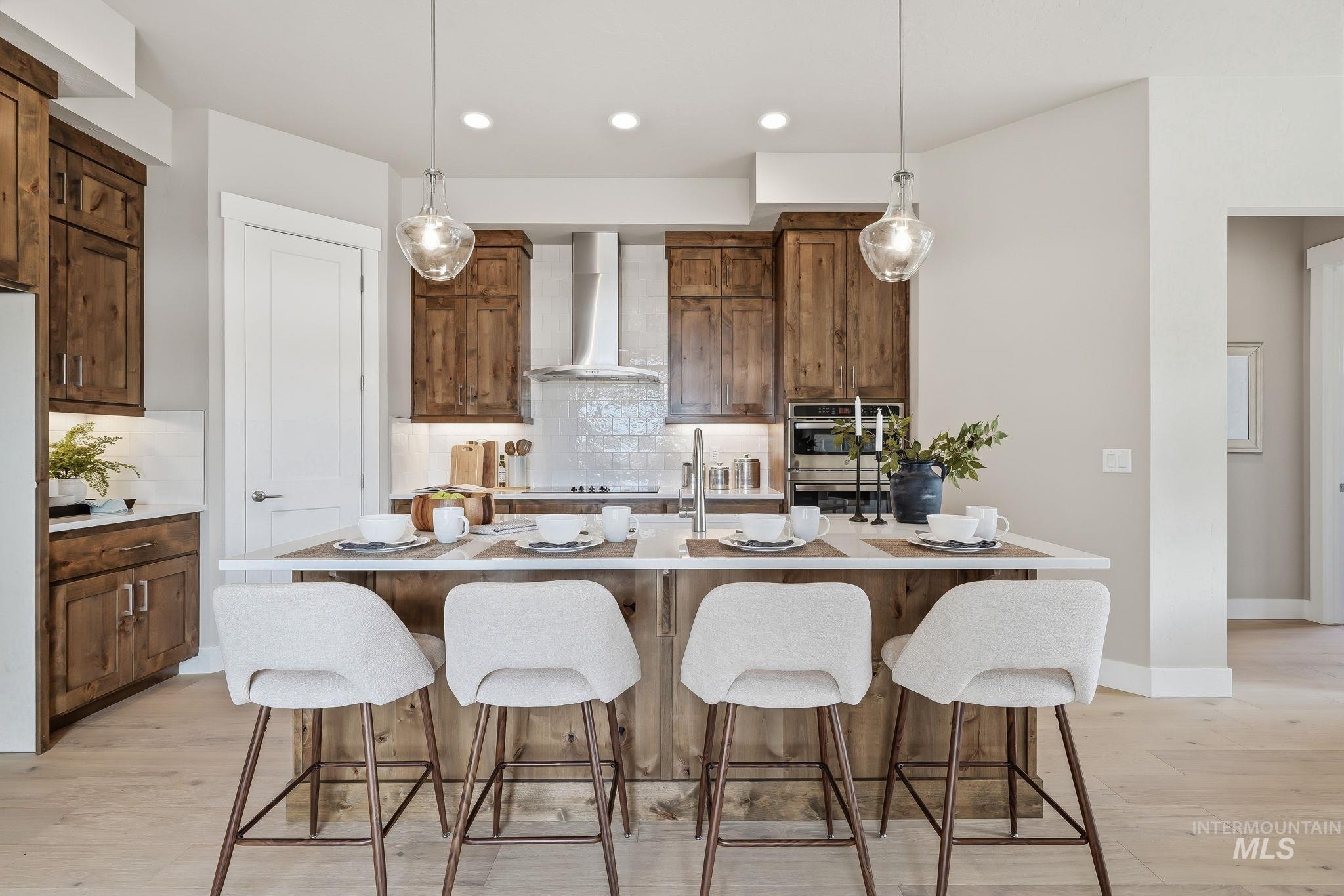 470 South Radiator Way Boise, ID 83716 - Photo 19 of 50 Kitchen featuring a central island with countertop seating, wood-finish cabinetry, a tile backsplash, stainless steel appliances, and pendant lighting
