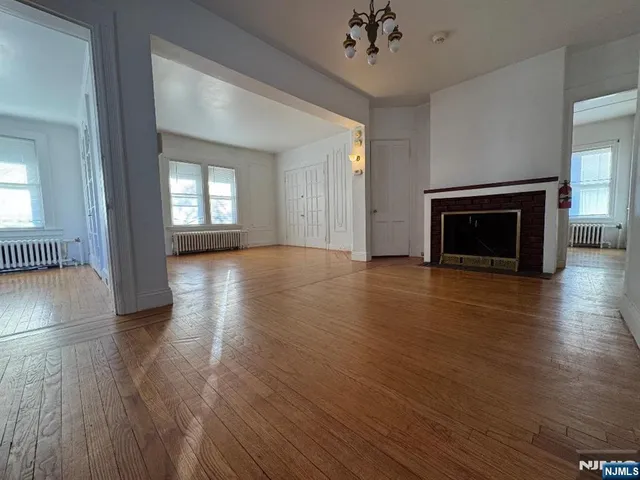 an empty room with wooden floor a fireplace and windows