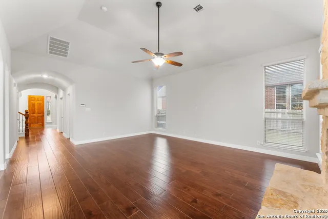 a view of a room with wooden floor ceiling fan and window