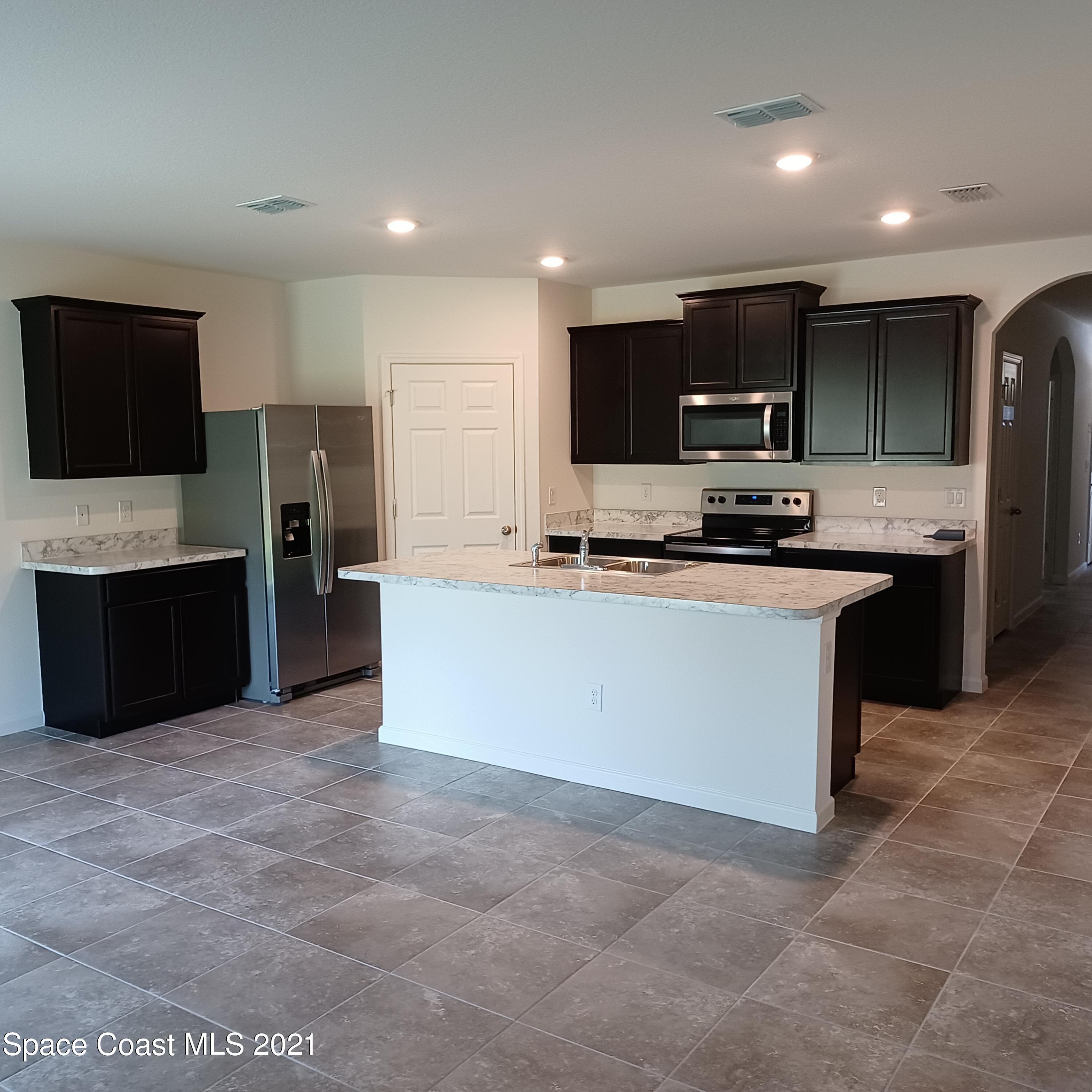 6558 Marble Road Cocoa, FL 32927 - Photo 2 of 16 a kitchen with stainless steel appliances a sink a stove a microwave a refrigerator a counter top space and cabinets
