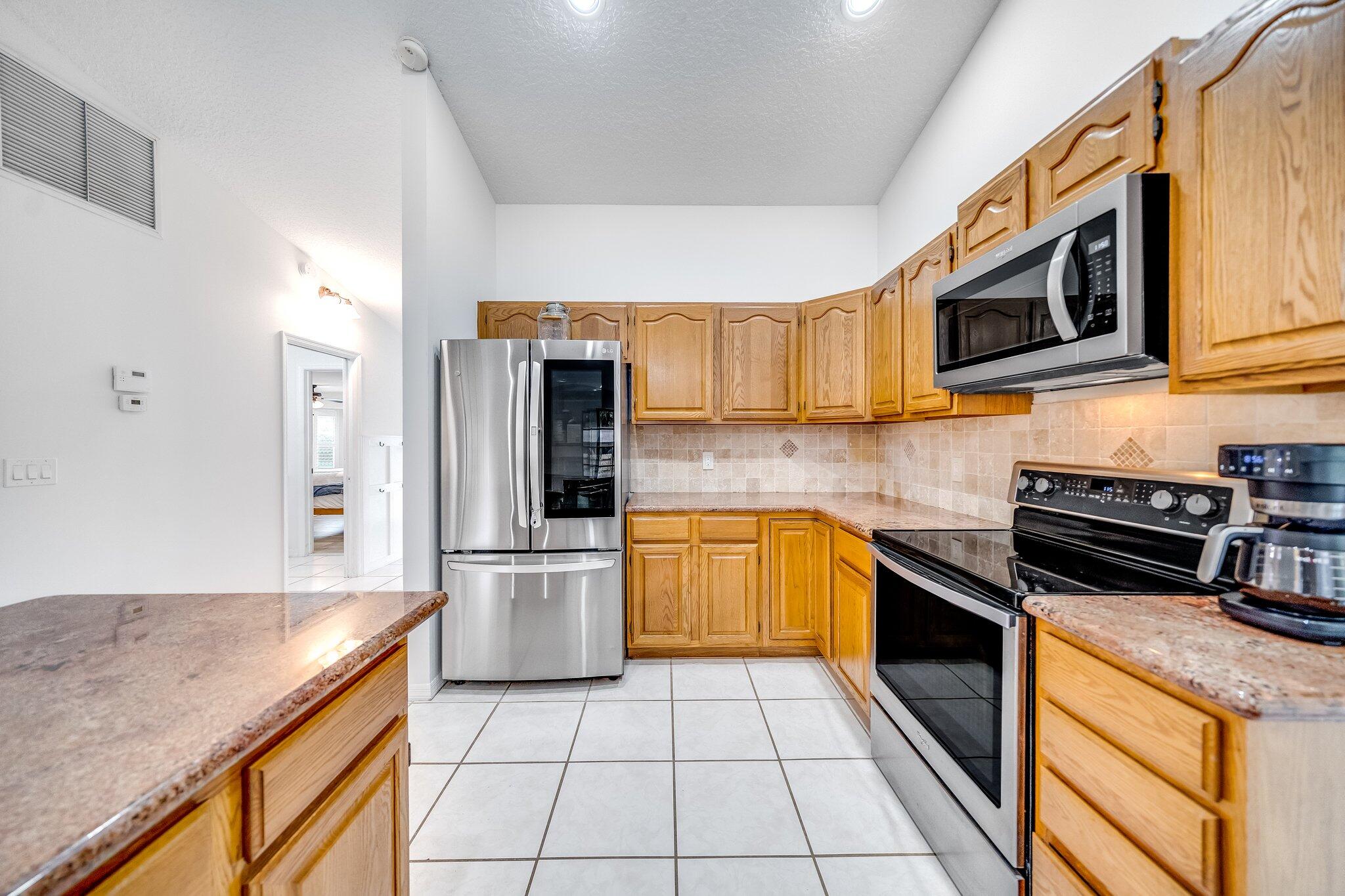 9268 Rodeo Drive Lake Worth, FL 33467 - Photo 11 of 66 a kitchen with stainless steel appliances granite countertop a stove a sink and a microwave
