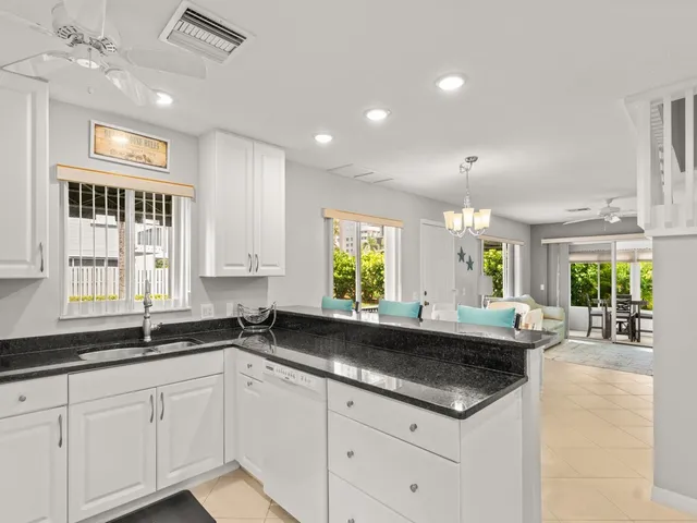a kitchen with granite countertop a sink white cabinets and window