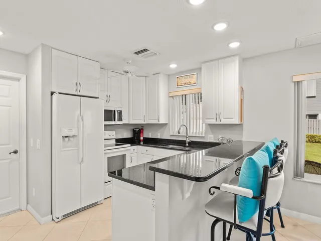 a kitchen with granite countertop white cabinets and refrigerator