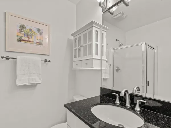 a bathroom with a granite countertop sink a mirror a vanity and a shower