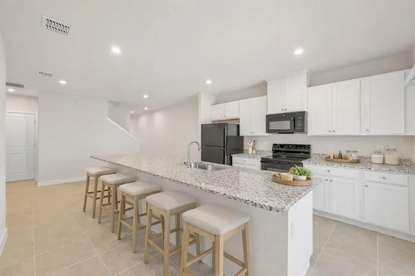 a large kitchen with stainless steel appliances a sink a stove a microwave a refrigerator and cabinets