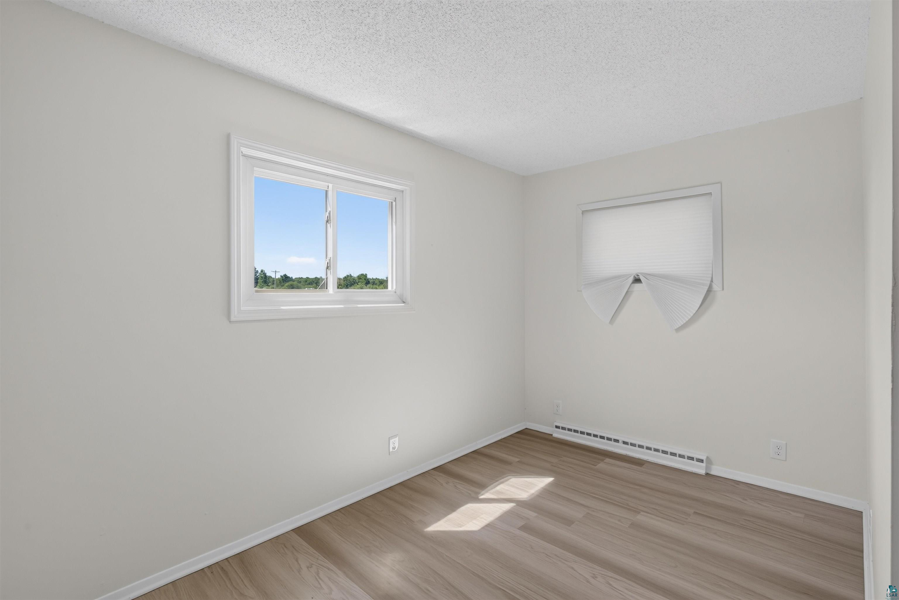 5868 Rice Lake Road Duluth, MN 55803 - Photo 22 of 39 Bright room featuring wood-finish flooring, white walls, and a textured ceiling