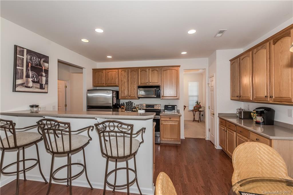 242 Garnet Court Fort Mill, SC 29708 - Photo 9 of 22 a kitchen with stainless steel appliances granite countertop a sink a stove a refrigerator cabinets and a dining table with wooden floor