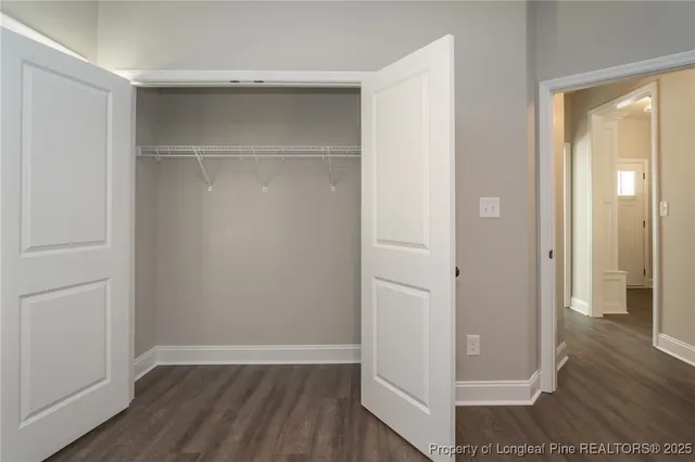 an empty room with wooden floor & closet area
