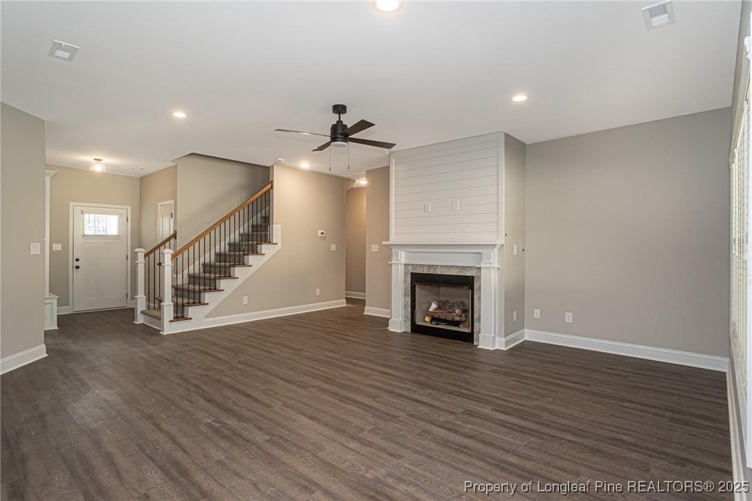 229 August Lane Raeford, NC 28376 - Photo 6 of 39 an empty room with wooden floor staircase and a fireplace