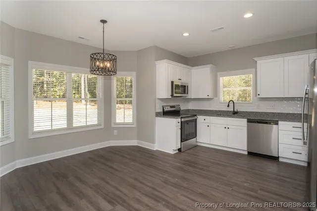 a kitchen with granite countertop stainless steel appliances cabinets and a wooden floor