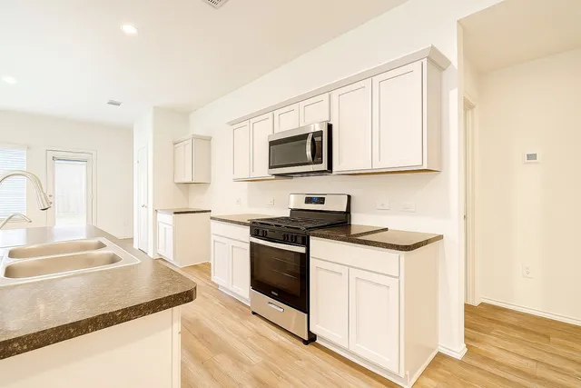 a kitchen with stainless steel appliances granite countertop a stove a sink and a microwave