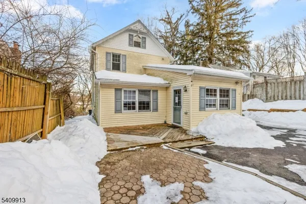 a view of a white house with a large tree next to a yard