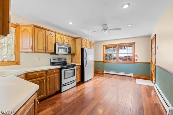 a kitchen with stainless steel appliances granite countertop a refrigerator a sink dishwasher a stove and white countertops with wooden floor