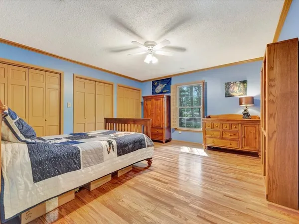 a spacious bedroom with a bed and wooden floor