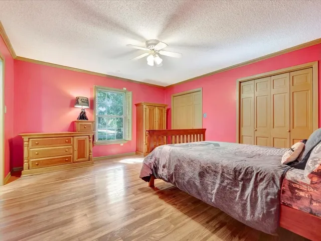 a bedroom with a bed and dresser with wooden floor