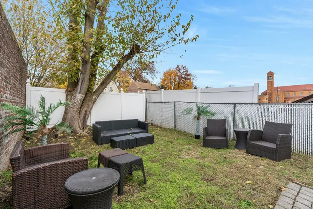 a view of a backyard with table and chairs potted plants and a large tree