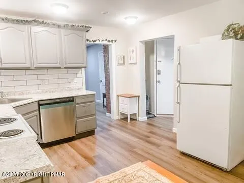 a kitchen with granite countertop a refrigerator a sink and dishwasher