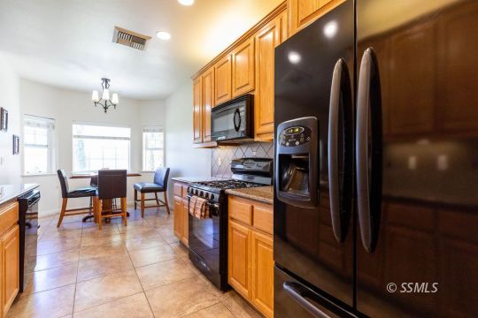 409 Acacia Street Ridgecrest, CA 93555 - Photo 10 of 34 a kitchen with stainless steel appliances granite countertop a refrigerator a stove top oven and a dining table