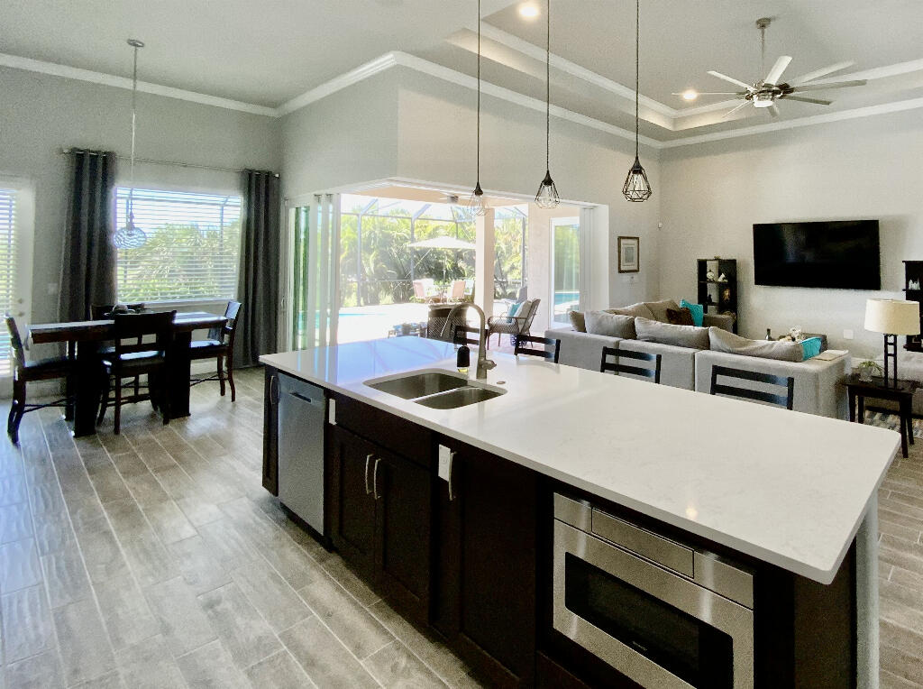 4644 Capri Lane Melbourne, FL 32935 - Photo 13 of 43 a kitchen with kitchen island a sink dining table and chairs