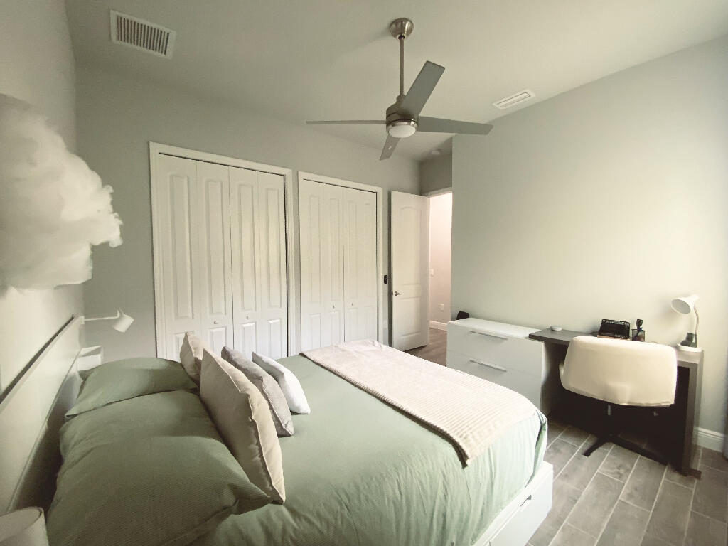 4644 Capri Lane Melbourne, FL 32935 - Photo 26 of 43 a bed sitting in a bedroom next to a window and a chandelier