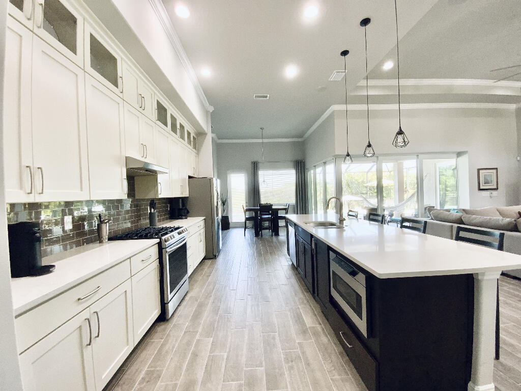 4644 Capri Lane Melbourne, FL 32935 - Photo 10 of 43 a large kitchen with stainless steel appliances and white cabinets