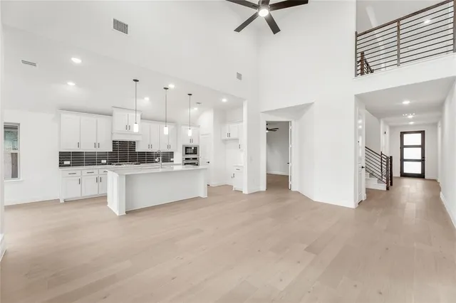 a large white kitchen with kitchen island a stove a sink a refrigerator and white cabinets