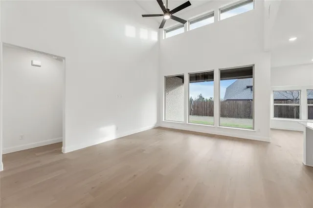 an empty room with wooden floor a ceiling fan and windows