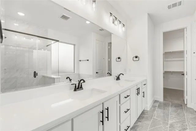 a bathroom with a double vanity sink mirror and shower