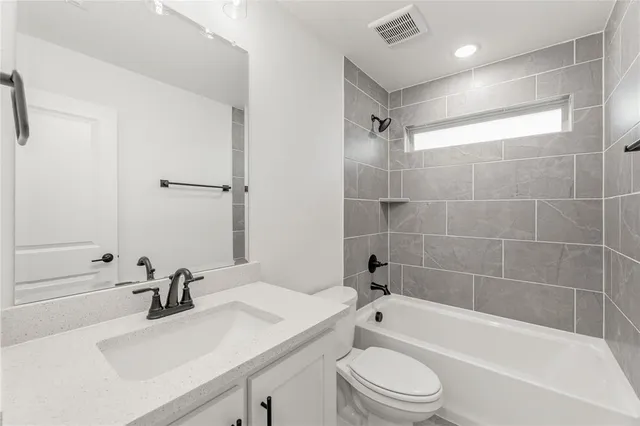 a bathroom with a bathtub shower sink vanity mirror and toilet