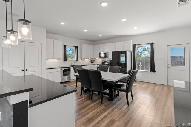 a kitchen with stainless steel appliances kitchen island granite countertop a stove a sink a oven a dining table and chairs