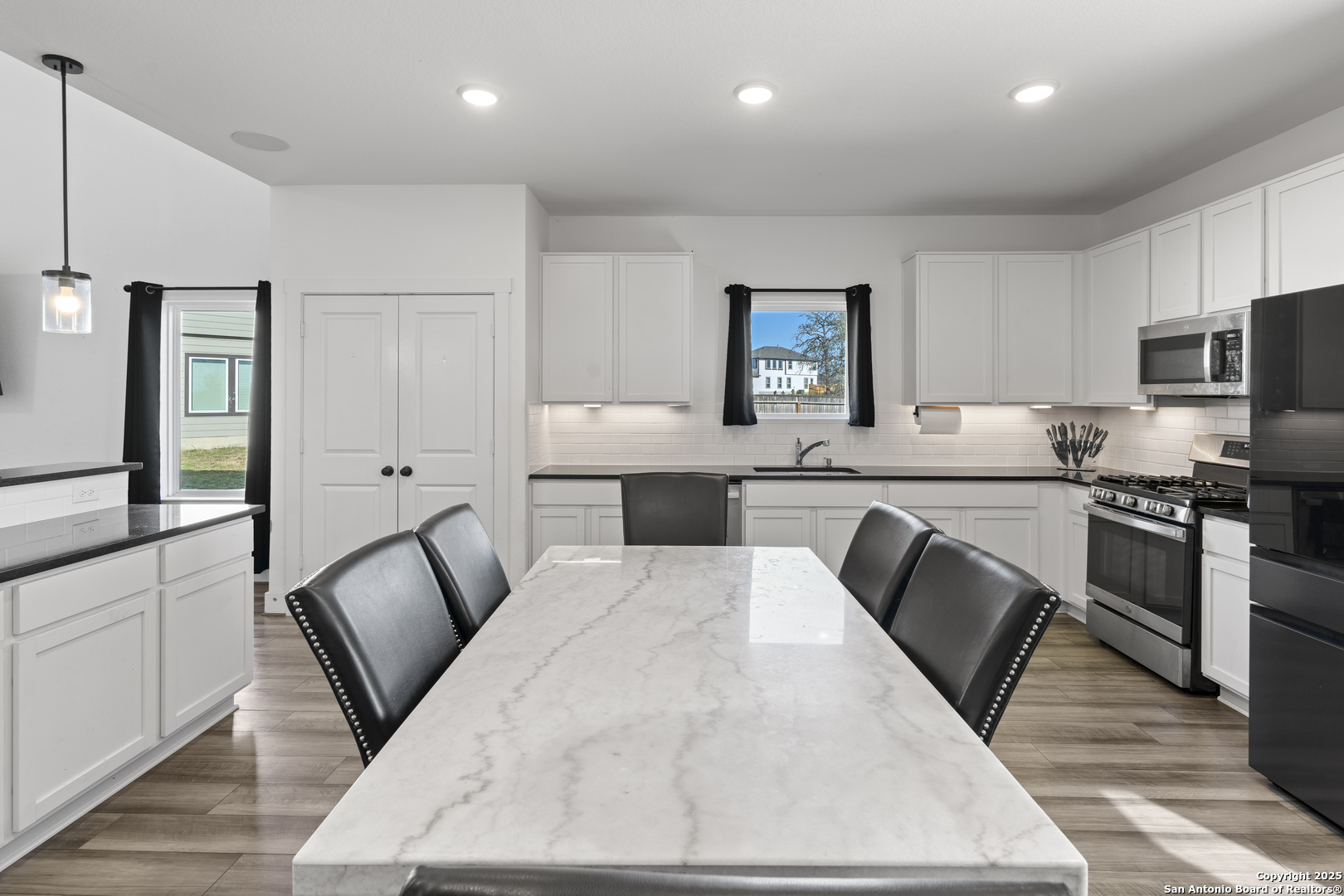 8823 Catnip Pass Elmendorf, TX 78112 - Photo 18 of 34 a kitchen with stainless steel appliances kitchen island granite countertop a stove a sink a oven a dining table and chairs