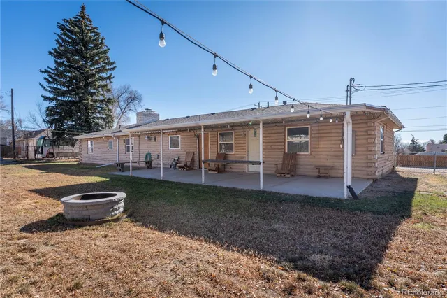 a view of a white house next to a yard with plants and large trees