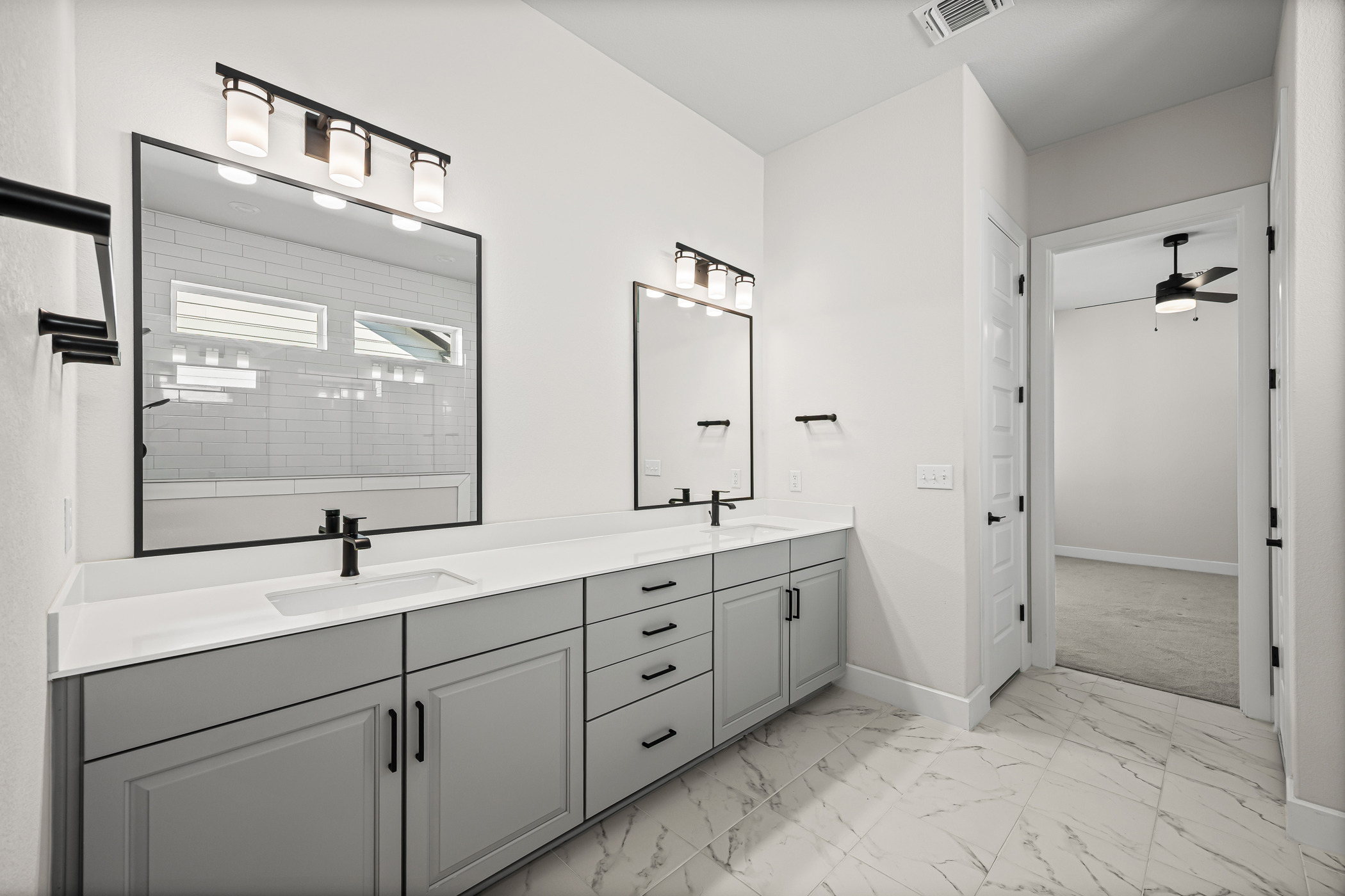 5806 Rangeland Road Austin, TX 78747 - Photo 7 of 34 Dual vanities with sleek cabinetry and elegant marble-patterned flooring define this refined bathroom space.