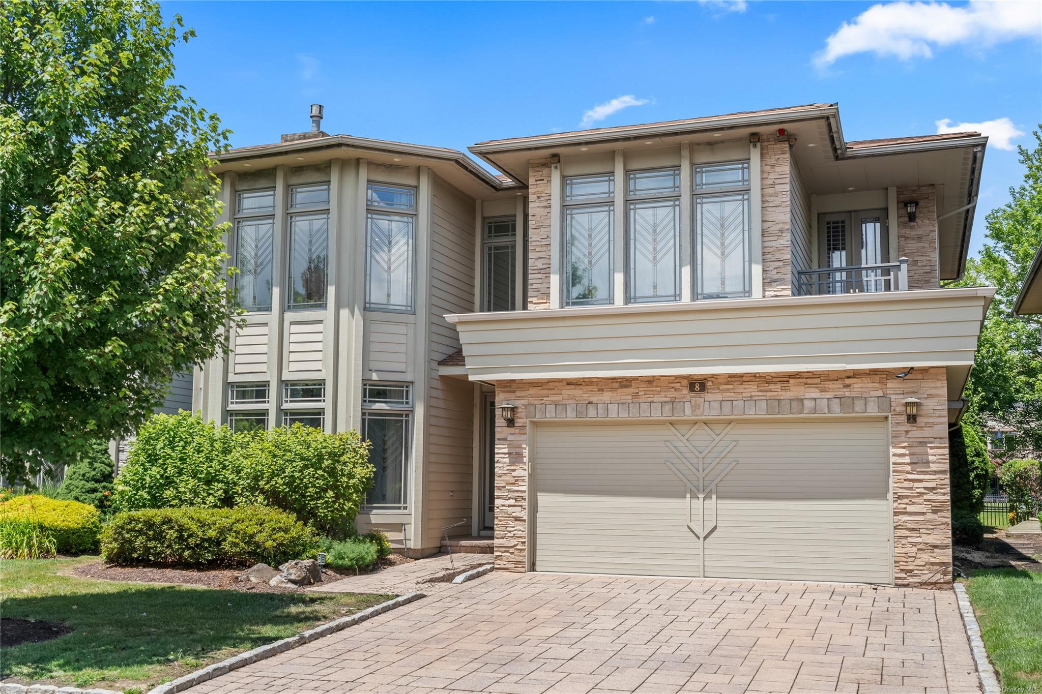 8 Holiday Pond Road Jericho, NY 11753 - Photo 1 of 43 View of front of home featuring decorative driveway, an attached garage, a balcony, and stone siding