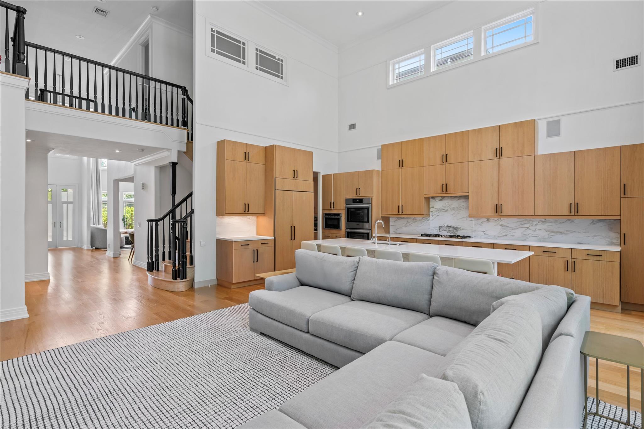 8 Holiday Pond Road Jericho, NY 11753 - Photo 14 of 43 Living room featuring stairway, light wood finished floors, a towering ceiling, and ornamental molding