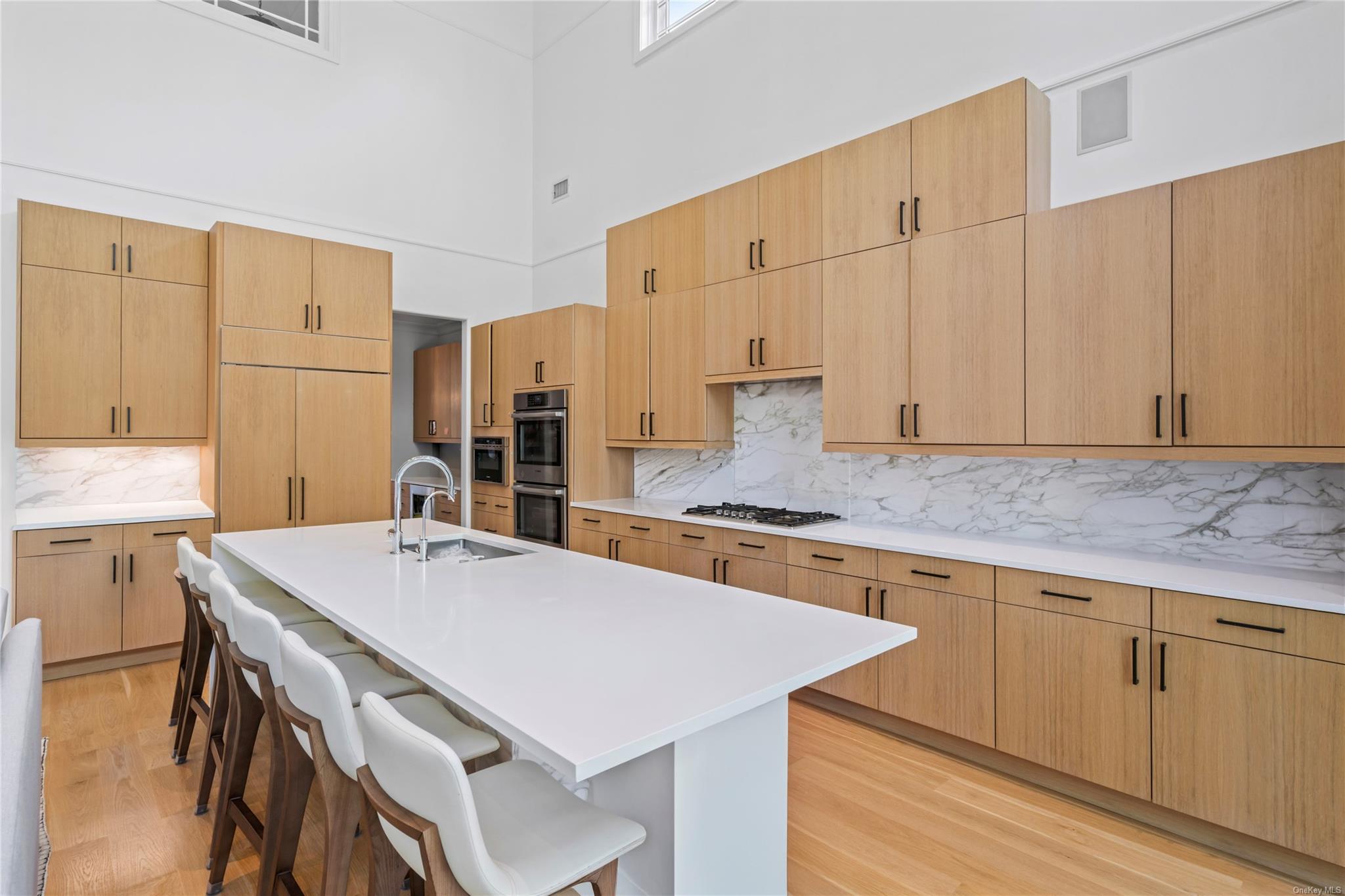 8 Holiday Pond Road Jericho, NY 11753 - Photo 15 of 43 Kitchen with a high ceiling, stainless steel appliances, light wood-style floors, a kitchen bar, and backsplash