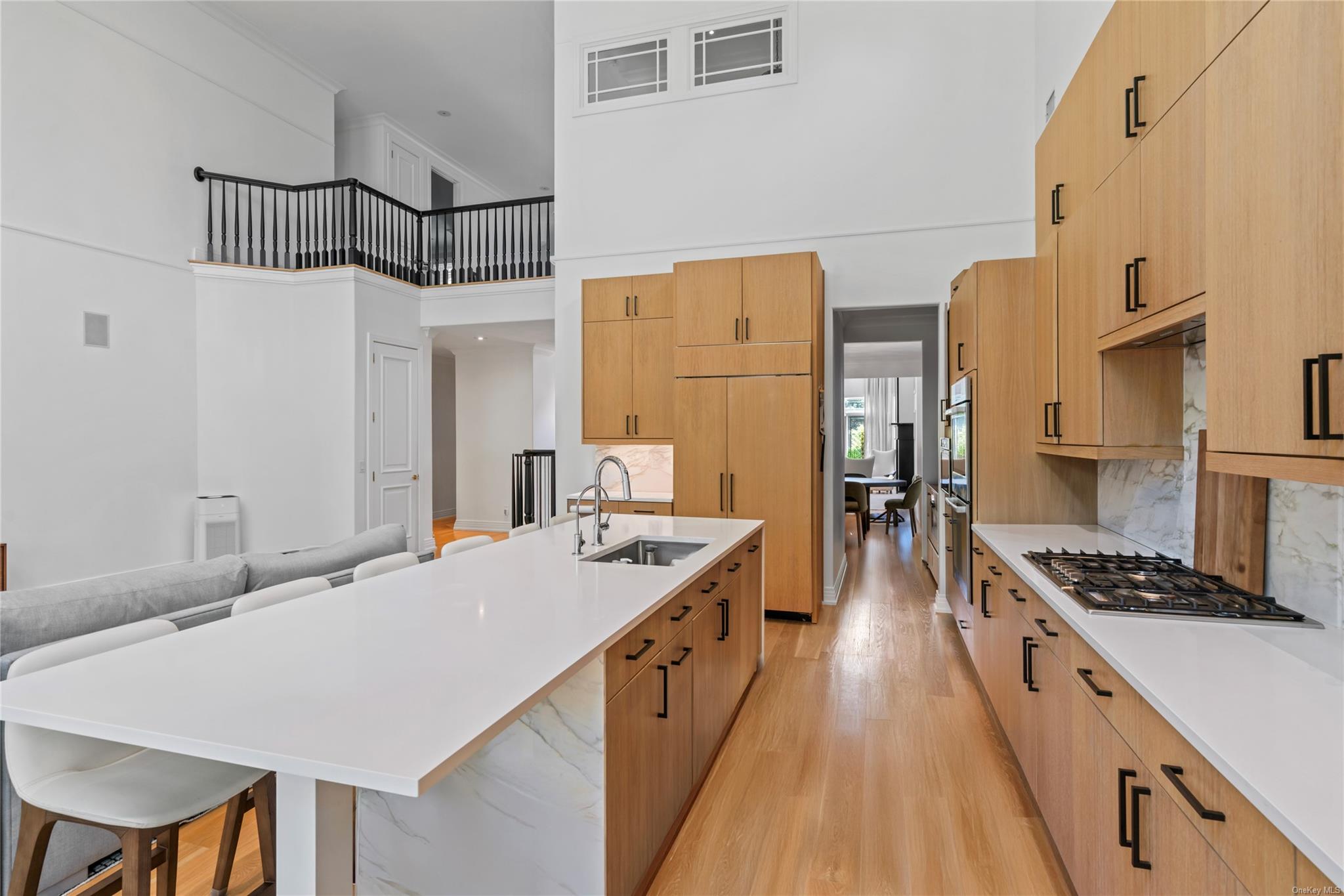 8 Holiday Pond Road Jericho, NY 11753 - Photo 16 of 43 Kitchen with stainless steel gas stovetop, a towering ceiling, light wood finished floors, light countertops, and a kitchen breakfast bar