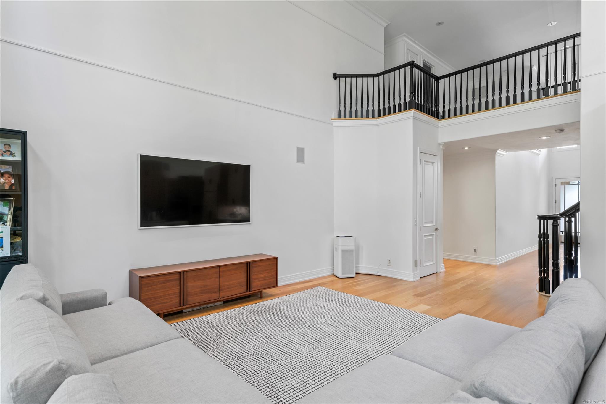 8 Holiday Pond Road Jericho, NY 11753 - Photo 17 of 43 Living room featuring wood finished floors, a high ceiling, and ornamental molding