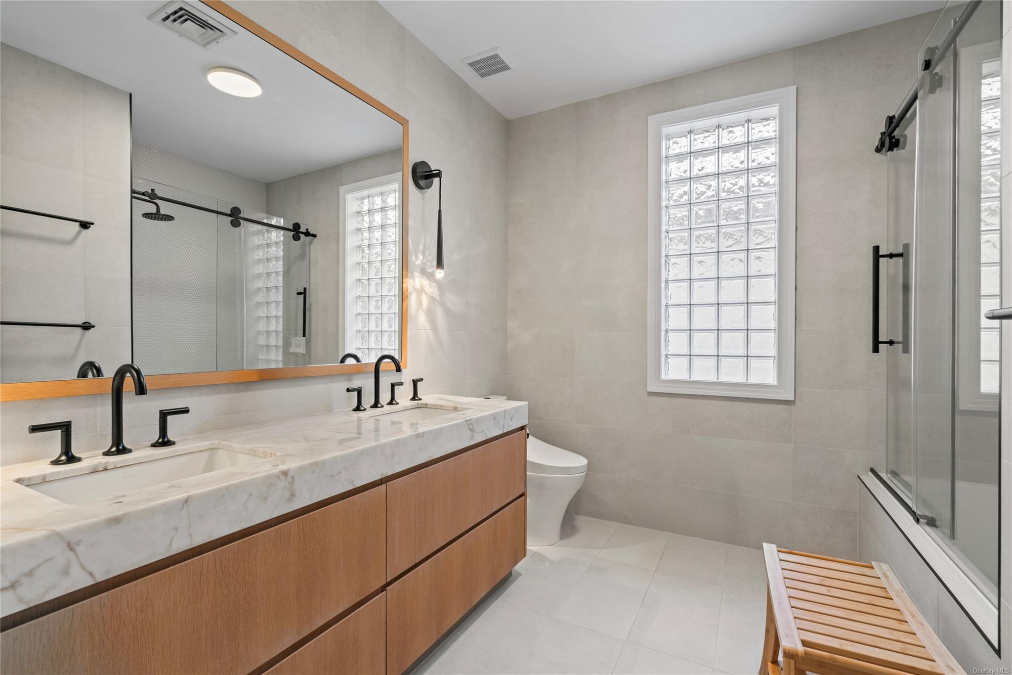 8 Holiday Pond Road Jericho, NY 11753 - Photo 28 of 43 Bathroom featuring double vanity, shower / bath combination with glass door, and tile walls