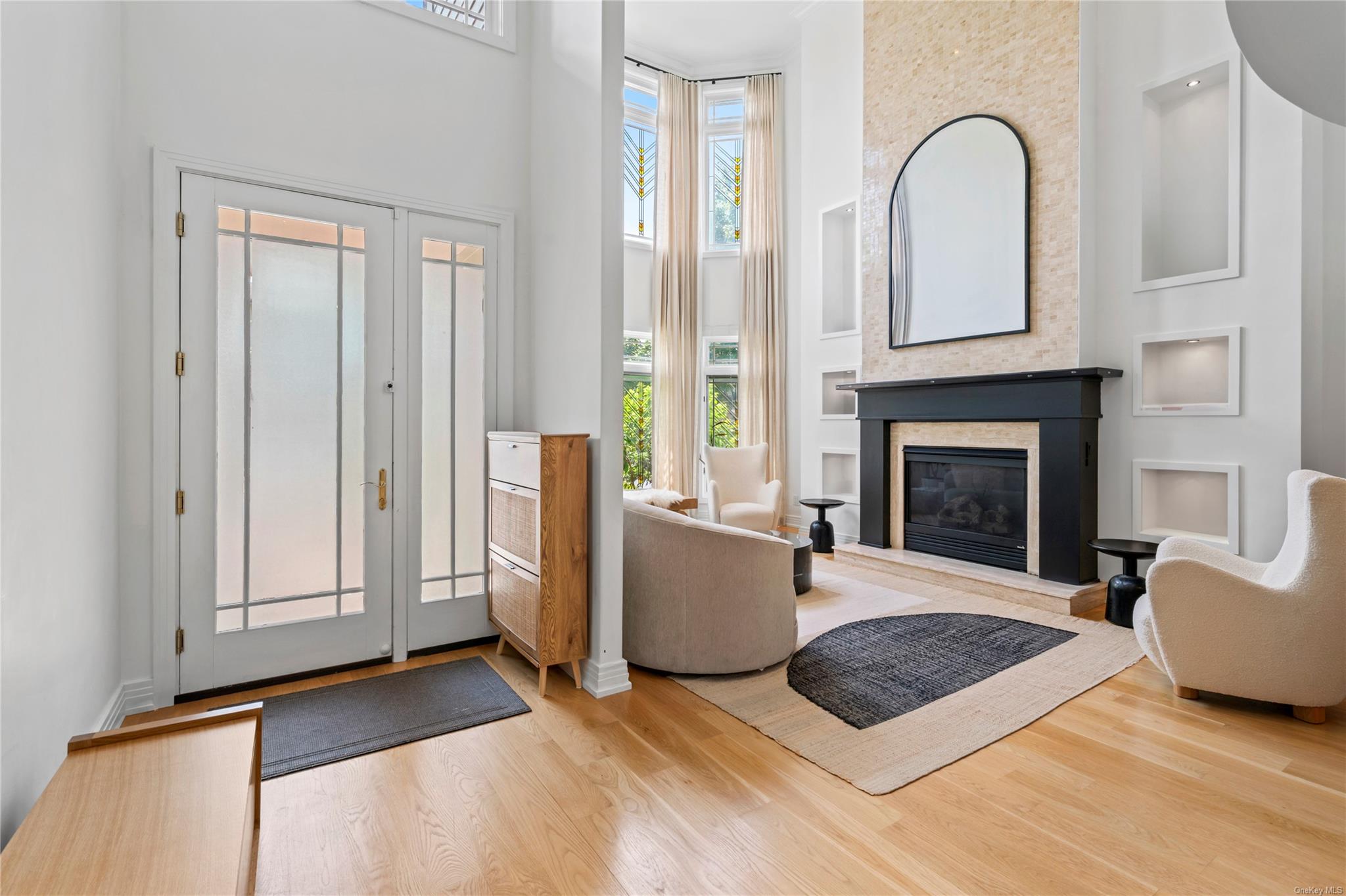 8 Holiday Pond Road Jericho, NY 11753 - Photo 5 of 43 Foyer entrance featuring a towering ceiling, wood finished floors, plenty of natural light, and a glass covered fireplace