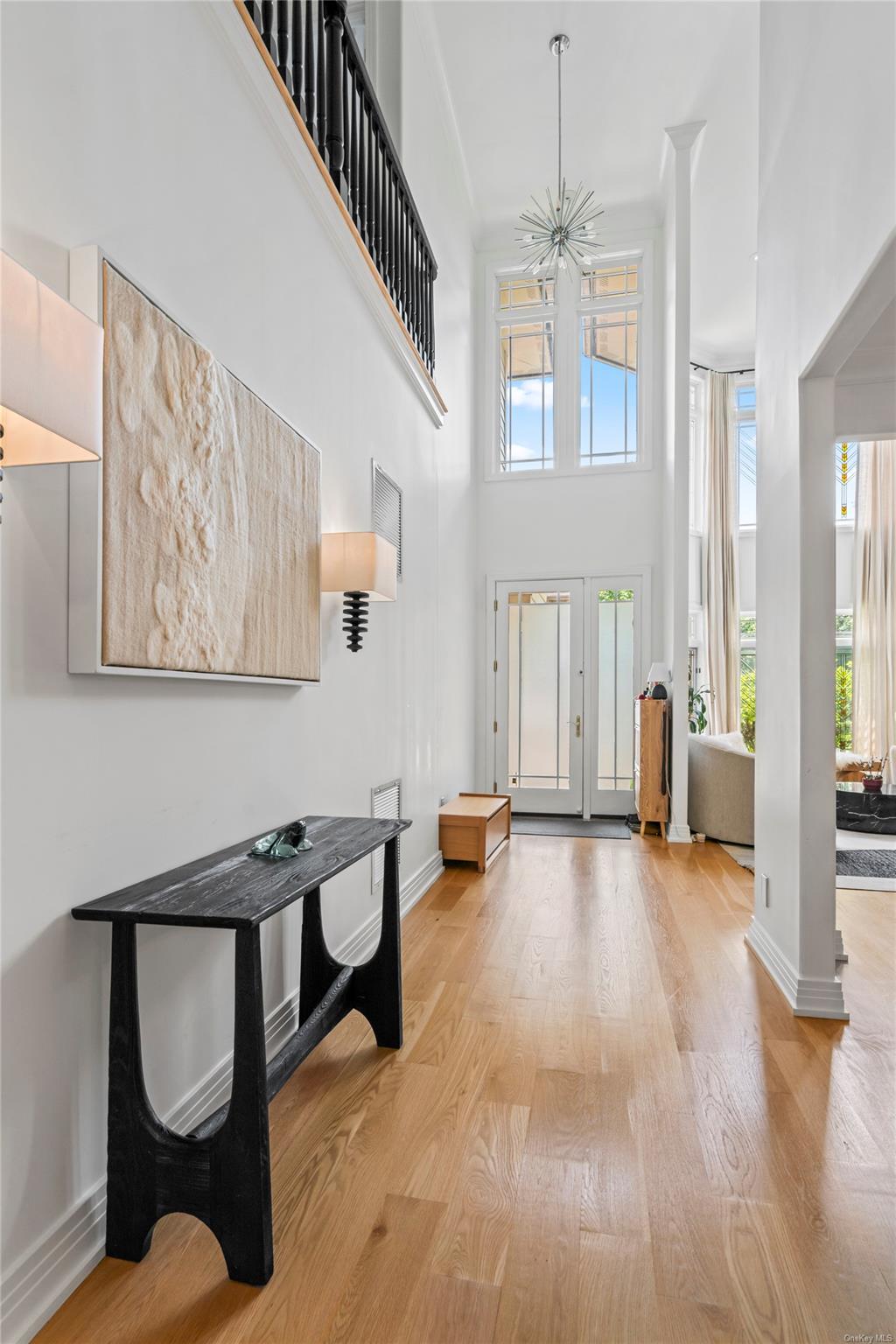 8 Holiday Pond Road Jericho, NY 11753 - Photo 6 of 43 Entrance foyer featuring light wood-style flooring, healthy amount of natural light, a high ceiling, ornate columns, and a chandelier