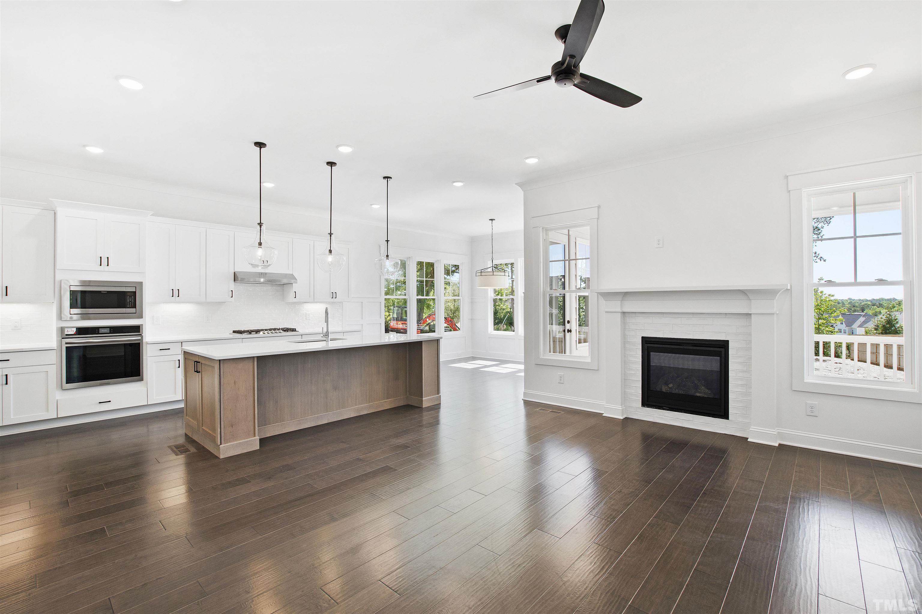 7512 Pinecrest Road Raleigh, NC 27613 - Photo 6 of 47 an open kitchen with a fireplace and wooden floor