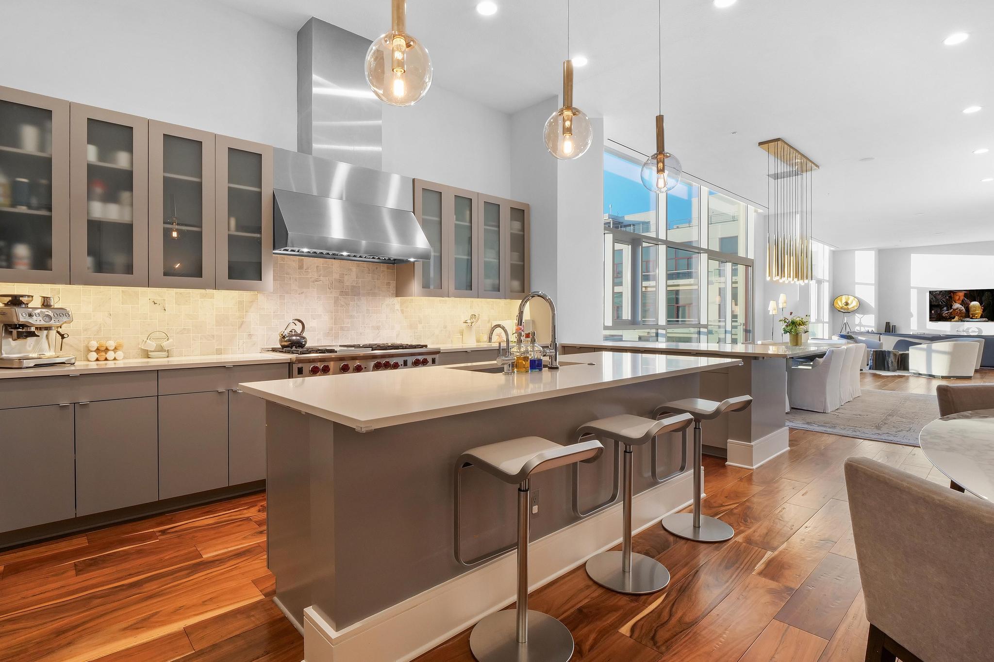 555 East 5th Street, Unit 3022 Austin, TX 78701 - Photo 40 of 40 Kitchen with gray cabinetry, decorative light fixtures, open floor plan, a breakfast bar area, and an island with sink