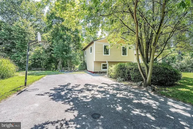 a view of a house with a yard and large trees