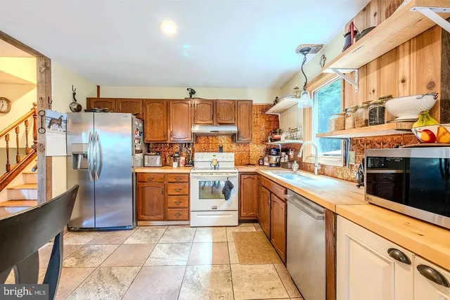 a kitchen with stainless steel appliances granite countertop a refrigerator a oven a sink with the countertops and couches