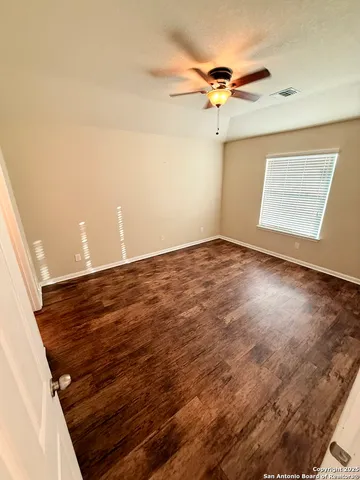 an empty room with a ceiling fan and wooden floor