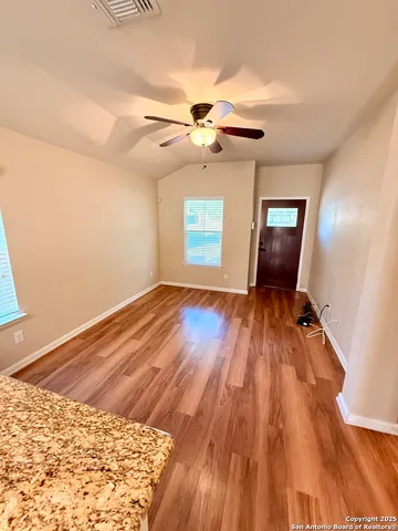 a view of empty room with wooden floor and fan