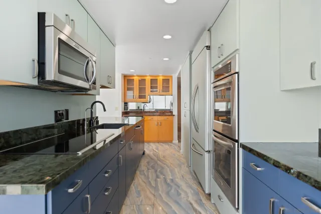 a kitchen with stainless steel appliances granite countertop a refrigerator a stove and a sink with wooden floor
